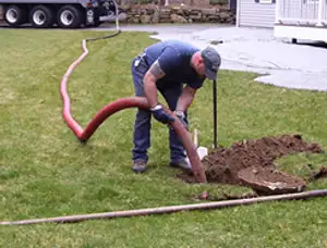 Septic pumping technician servicing a residential septic tank with a vacuum hose in Hartford, CT